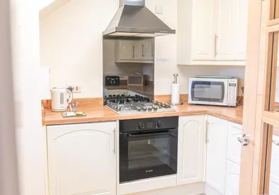 a kitchen with a stove and a microwave at Tiggs Place, 5 Howrahs Court in Keswick