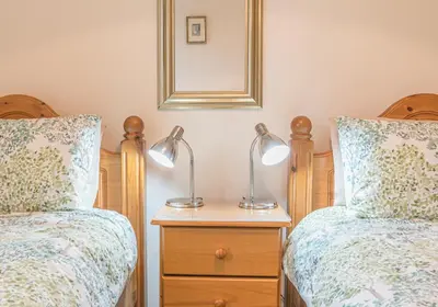 two beds in a bedroom with two lamps on a nightstand at Tiggs Place, 5 Howrahs Court in Keswick