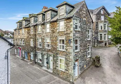 a large stone building with white windows on a street at Withesike, Derwent House in Keswick