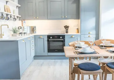 a kitchen with blue cabinets and a wooden table at Victoria Apartment, Derwent House in Keswick