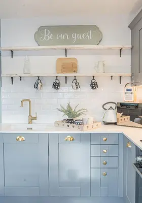 a kitchen with blue cabinets and a sign that reads be our guest at Victoria Apartment, Derwent House in Keswick