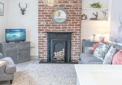 a living room with a brick fireplace and a tv at Victoria Apartment, Derwent House in Keswick
