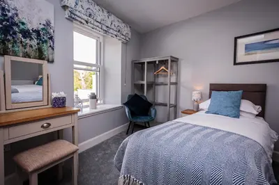 a bedroom with a bed and a mirror and a window at The Kenmuir Arms Hotel in New Luce
