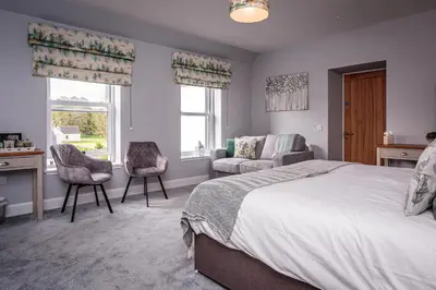 a bedroom with a bed and a desk and chairs at The Kenmuir Arms Hotel in New Luce