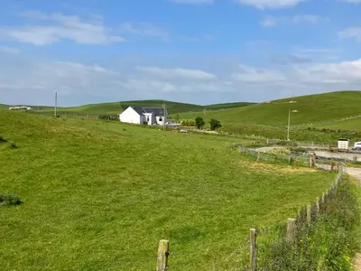 a field of green grass with a house in the background at Cherry Tree Cottage in Stranraer