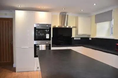 a kitchen with black counter tops and white cabinets at The Blue House holiday home in Egremont