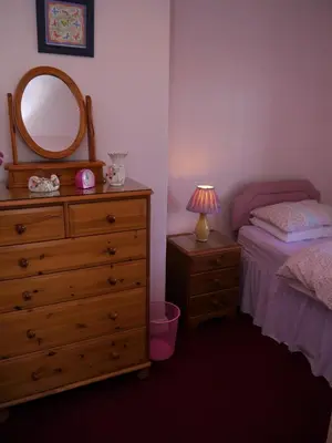a bedroom with a bed and a dresser with a mirror at Woodhall Cottage in Annan