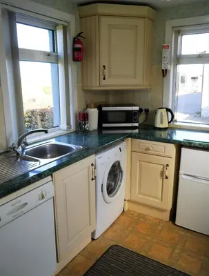 a kitchen with a sink and a washing machine at Woodhall Cottage in Annan