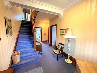 a hallway with a staircase with a lamp and a chair at Beautiful Period Property in Central Location - Pass the Keys in Maxwelltown