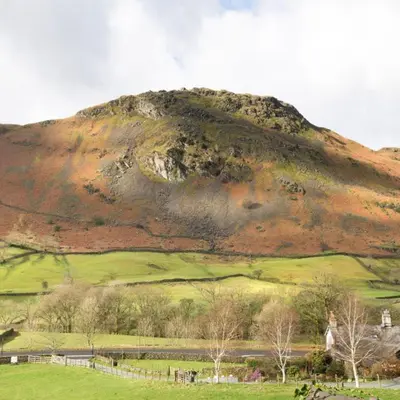 a hill with a green field and a mountain at Bramrigg House in Grasmere