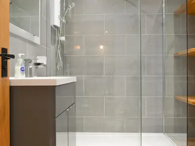 a bathroom with a glass shower with a sink at Bumble Cottage in Cockermouth