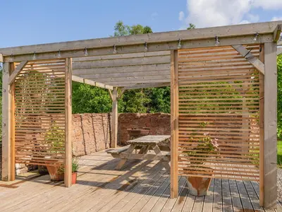a wooden pergola with a picnic table on a deck at Cleugh Foot in Longtown