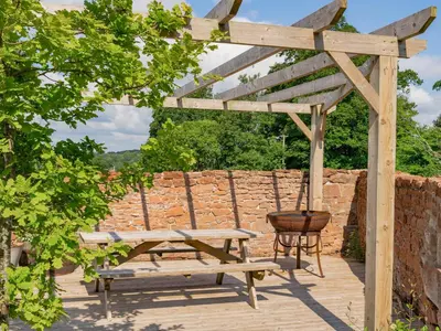 a wooden pergola with a bench and a barrel at Cleugh Foot in Longtown