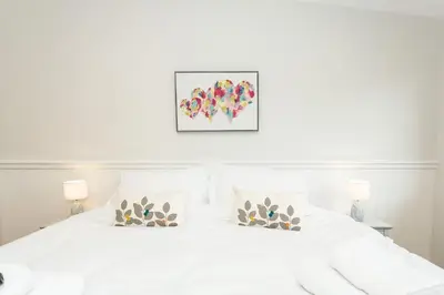 a white bedroom with a white bed with two lamps at Ocean Drive in Gatehouse of Fleet