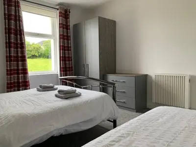 a bedroom with two beds and a window at 10 Burns Street, Tarbolton KA5 5RA in Tarbolton