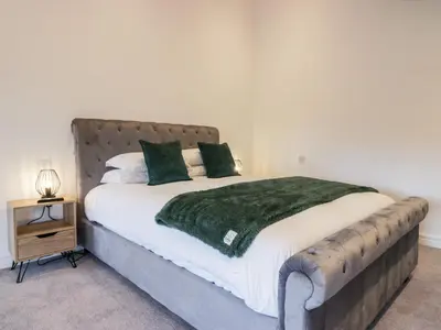 a bedroom with a large bed with a green blanket at The Bay Tree in Penrith