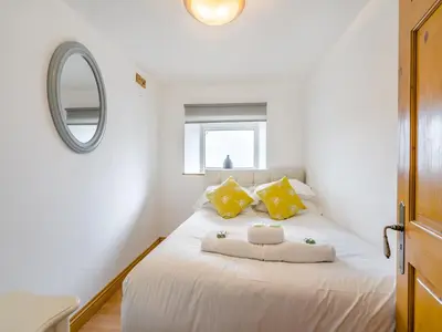 a bedroom with a white bed with yellow pillows and a mirror at Ben Ma Cree in Portpatrick
