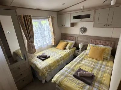 two beds in a small room next to a window at Luxury Lake District Holiday Lodge-Sleeps 4 in Cockermouth