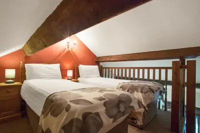 two beds in a room with orange walls at The Coppermines Mountain Cottages Sawyers, Carpenters, Millrace, Pelton Wheel, Sleeps 22 in Coniston