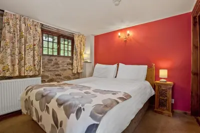 a bedroom with a large bed and a red wall at The Coppermines Mountain Cottages Sawyers, Carpenters, Millrace, Pelton Wheel, Sleeps 22 in Coniston