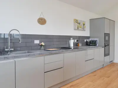a kitchen with white cabinets and stainless steel appliances at Old Byre Cottage - Uk43377 in Kirklinton