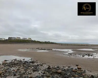 a beach with a bunch of rocks on the sand at Three Bedroom in Seascale