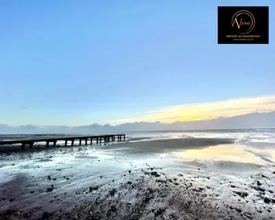 a beach with a pier in the water at Three Bedroom in Seascale