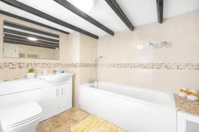 a bathroom with a tub and a toilet and a sink at Hollie's Beach House in Peel