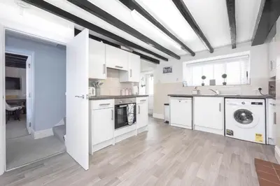 a kitchen with white cabinets and a washer and dryer at Hollie's Beach House in Peel