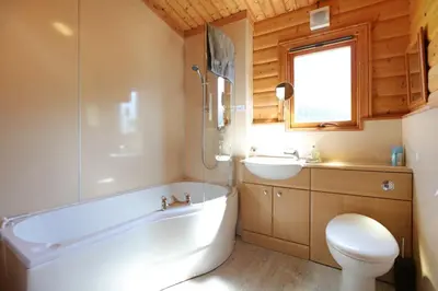a bathroom with a tub and a toilet and a sink at Birchlea in Kippford