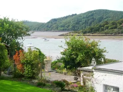 a house with a view of a river and a boat at The Bridge in Kippford