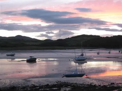 a group of boats sitting in the water at sunset at The Bridge in Kippford