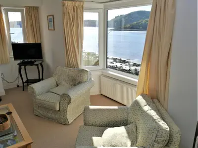 a living room with two chairs and a large window at The Bridge in Kippford