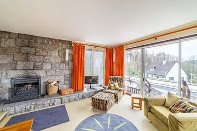 a living room with a fireplace and a stone wall at Bells View in Kippford