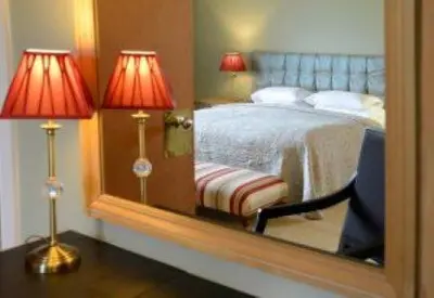 a mirror reflecting a bedroom with a bed and a chair at Mabie House Hotel in Dumfries