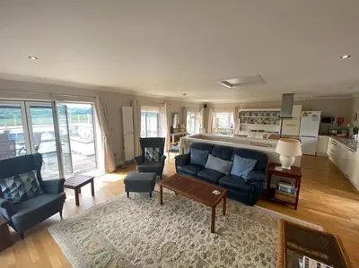 a living room with a blue couch and a kitchen at Phoenix Cottage in Kippford
