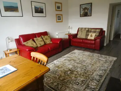 a living room with two red couches and a table at Barnacle in Mainsriddle