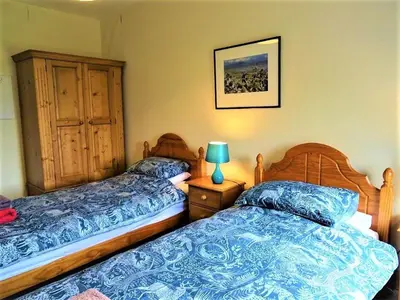 a bedroom with two beds and a lamp on a night stand at Barnacle in Mainsriddle