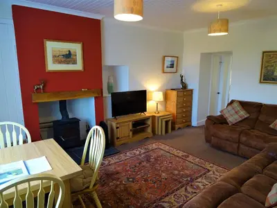 a living room with a couch and a television and a table at Shelduck Cottage in Mainsriddle