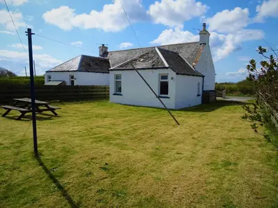 a white house with a picnic table in the yard at Shelduck Cottage in Mainsriddle