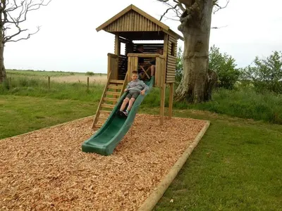 a young boy sliding down a slide on a playground at Shelduck Cottage in Mainsriddle