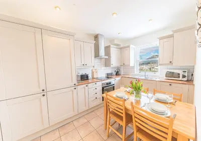 a kitchen with a table and chairs and a kitchen with white cabinets at 7 Greta Grove House in Keswick