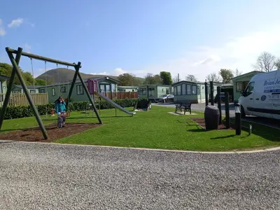 a park with a swing set and a van at Adorable Caravan in Western Lakes in Workington
