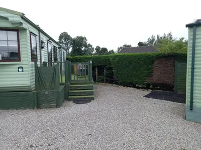 a house with a porch and stairs next to a yard at Adorable Caravan in Western Lakes in Workington