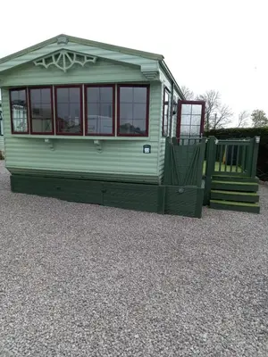 a green tiny house sitting on top of gravel at Adorable Caravan in Western Lakes in Workington