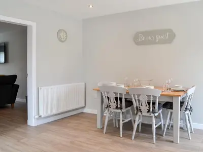 a dining room with a table and white chairs at Crofthouse - Uk43405 in Wigtown