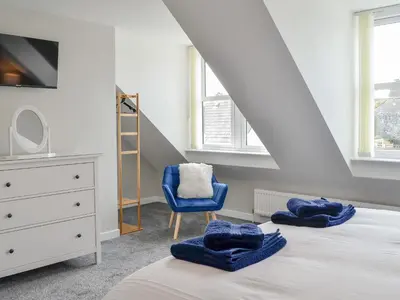 a bedroom with a bed and a blue chair at Crofthouse - Uk43405 in Wigtown