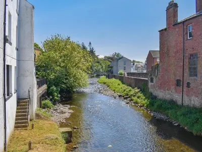 a river between two buildings in a town at Hatters Croft in Cockermouth