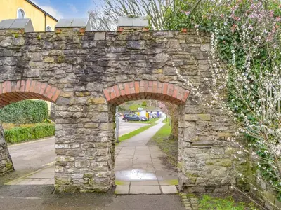 an old stone wall with three arches on a street at Hatters Croft in Cockermouth