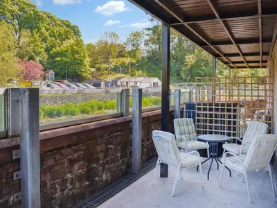 a patio with white chairs and a table and a view at Hatters Croft in Cockermouth